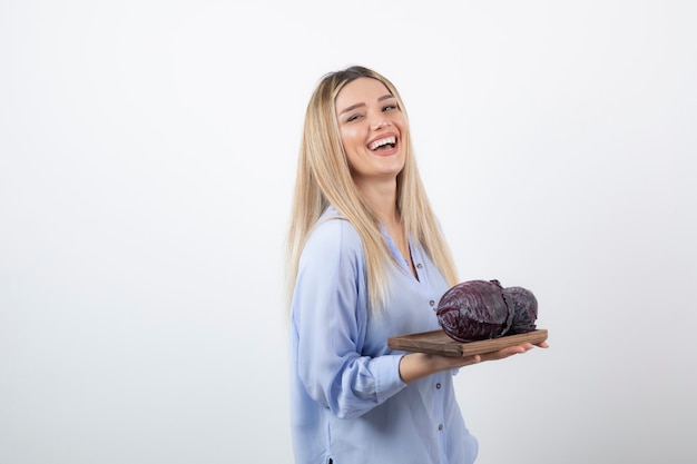 sonriente modelo de niña bonita de pie y sosteniendo el repollo.