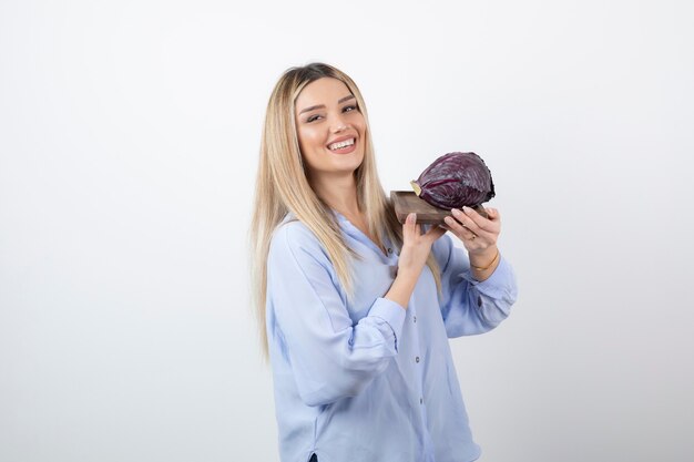 sonriente modelo de niña bonita de pie y sosteniendo el repollo.