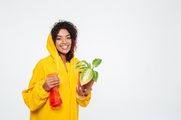 Sonriente mujer africana en gabardina con planta