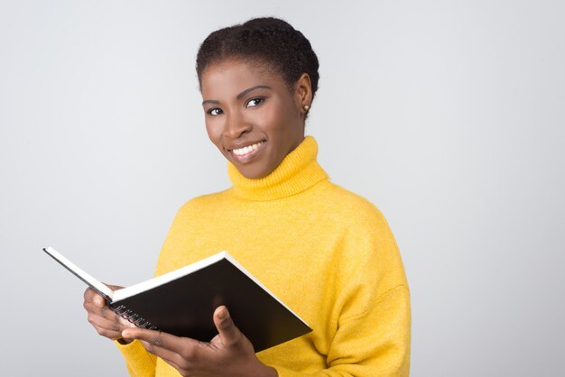 Sonriente mujer afroamericana con bloc de notas