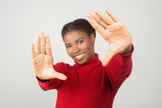 Sonriente mujer afroamericana haciendo marco de fotos con las manos