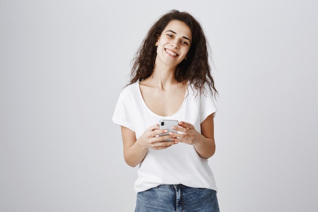 Sonriente mujer alegre mediante teléfono móvil, compras en línea