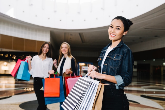 Sonriente mujer con amigos en el centro comercial