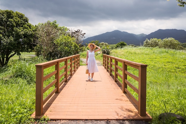 Foto gratuita sonriente mujer asiática caminando en la naturaleza en un día nublado