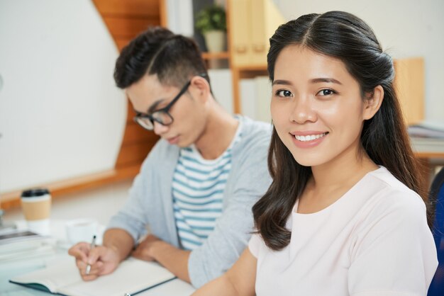 Sonriente mujer asiática con colega masculino en la mesa