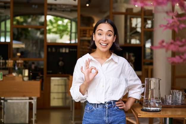Sonriente mujer asiática feliz empresaria recomendando café mostrando bien ok firmar en aprobación