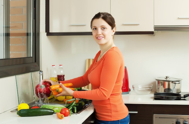 Sonriente mujer bonita lavar las verduras frescas