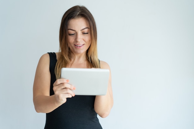 Sonriente mujer bonita navegando en la tableta. Señora leyendo noticias en tableta.