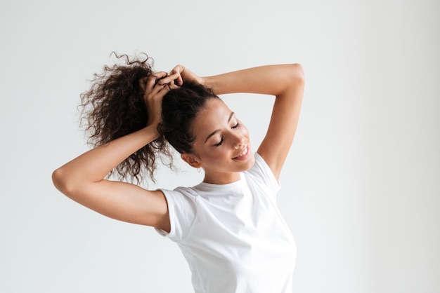 Foto gratuita sonriente mujer bonita con los ojos cerrados jugando con su cabello