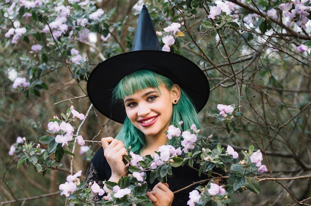 Sonriente mujer bruja con rama en flor