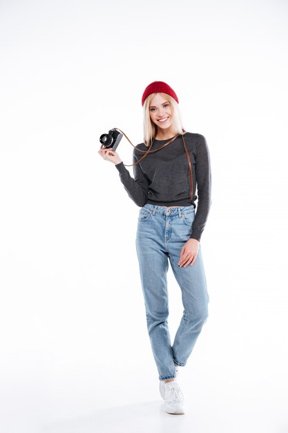 Sonriente mujer casual fotógrafo de pie y sosteniendo la cámara retro