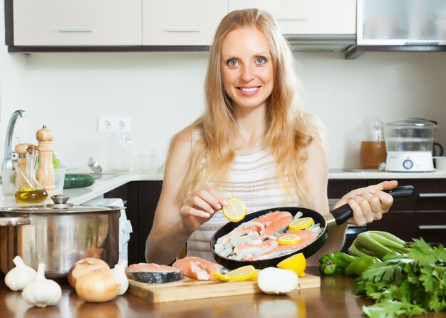 Sonriente mujer cocinar salmón con limón