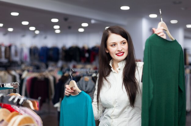 Sonriente mujer comprador con suéteres