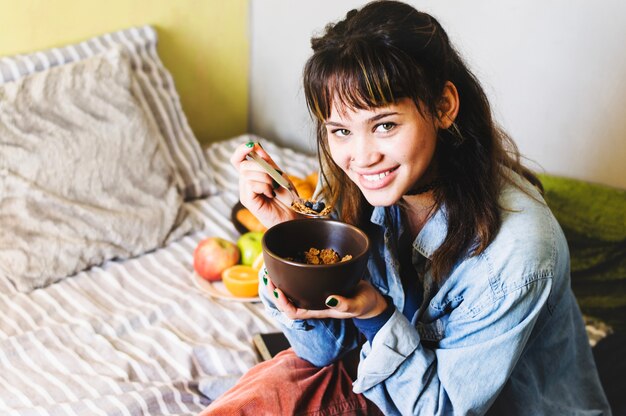 Sonriente mujer desayunando en la cama