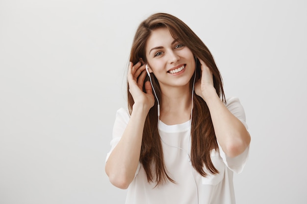 Sonriente mujer despreocupada escuchando música en auriculares