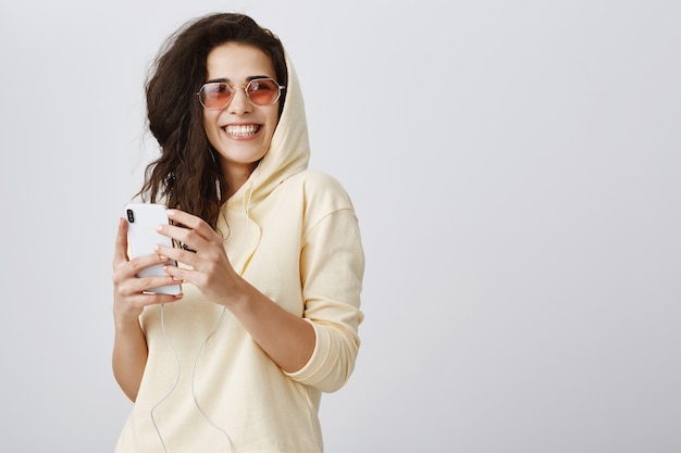 Sonriente mujer elegante mirando a otro lado mientras usa el teléfono móvil