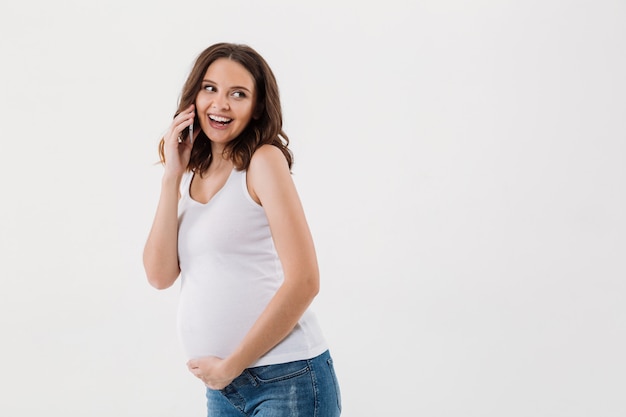 Sonriente mujer embarazada hablando por teléfono móvil