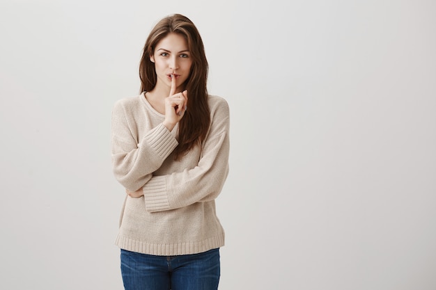 Sonriente mujer feliz escondiendo secreto, hacer un gesto de silencio para guardar silencio