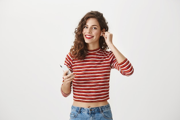 Sonriente mujer feliz escuchando música en auriculares inalámbricos, use la aplicación para teléfonos inteligentes