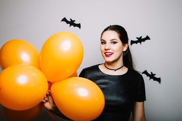 Sonriente mujer con globos en los murciélagos