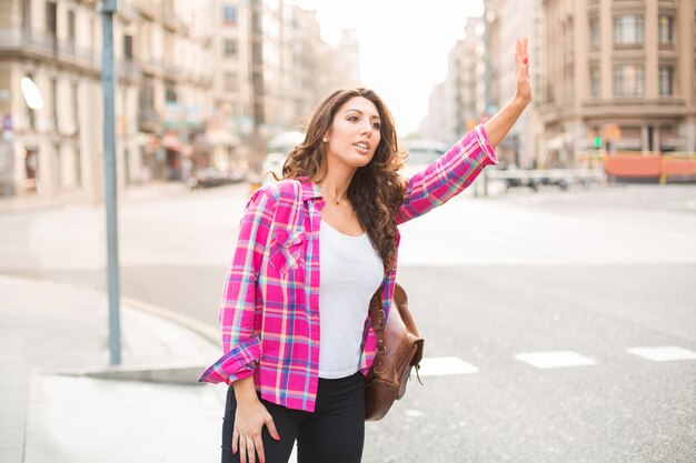 Sonriente mujer hermosa agitando a taxi