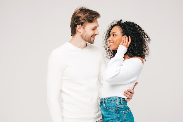 Sonriente mujer hermosa y su guapo novio. Familia multirracial alegre feliz que tiene momentos tiernos en gris