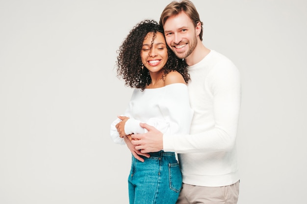 Sonriente mujer hermosa y su guapo novio. Familia multirracial alegre feliz que tiene momentos tiernos en gris