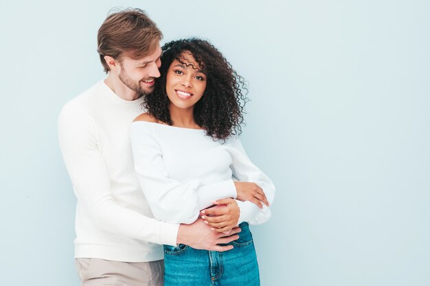 Sonriente mujer hermosa y su guapo novio. Familia multirracial alegre feliz que tiene momentos tiernos en gris