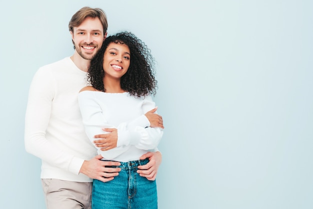 Sonriente mujer hermosa y su guapo novio. Familia multirracial alegre feliz que tiene momentos tiernos en gris