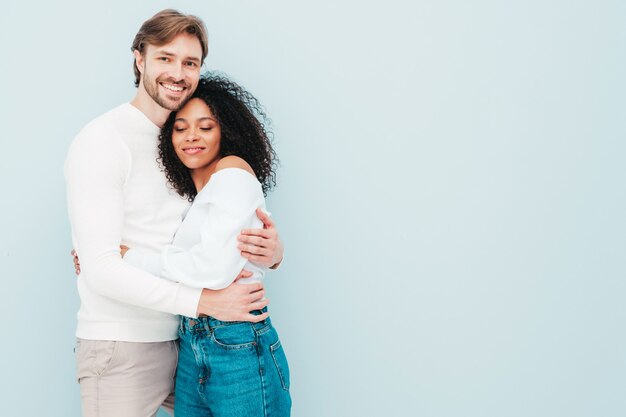 Sonriente mujer hermosa y su guapo novio. Familia multirracial alegre feliz que tiene momentos tiernos en gris