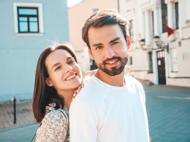 Sonriente mujer hermosa y su guapo novio Mujer en ropa casual de verano Familia alegre feliz Mujer divirtiéndose Pareja posando en el fondo de la calle Abrazándose unos a otros al atardecer