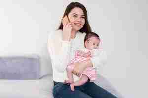 Foto gratuita sonriente mujer con hija y hablando por teléfono