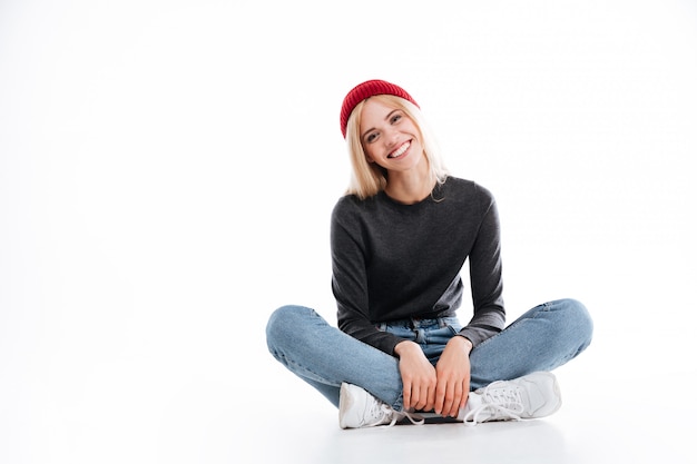 Sonriente mujer hipster sentada en el piso