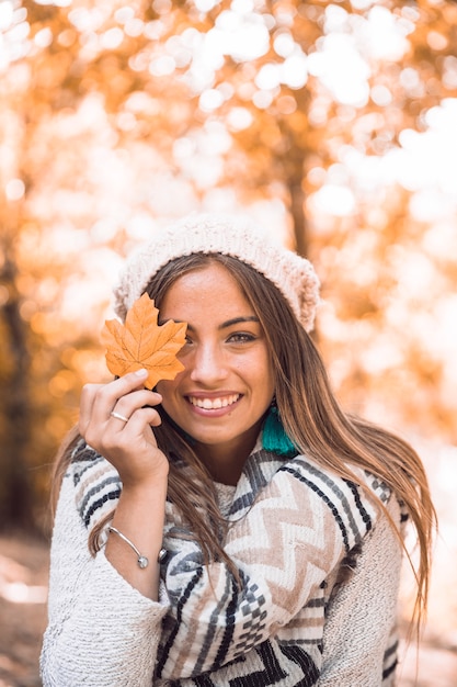 Sonriente mujer con hoja de otoño