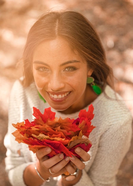 Sonriente mujer con hojas de otoño