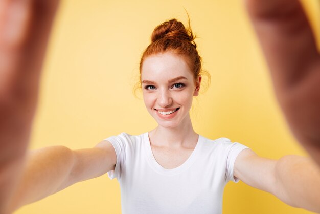 Sonriente mujer de jengibre en camiseta haciendo selfie