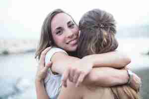 Foto gratuita sonriente mujer joven abrazando a su amiga