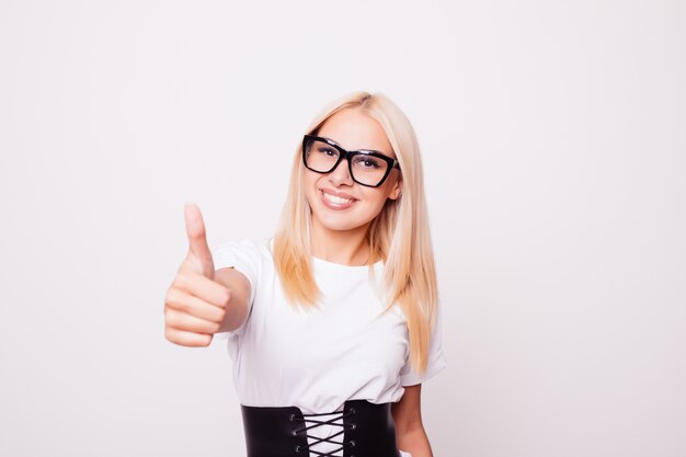 Sonriente mujer joven y bonita mostrando los pulgares para arriba aislado