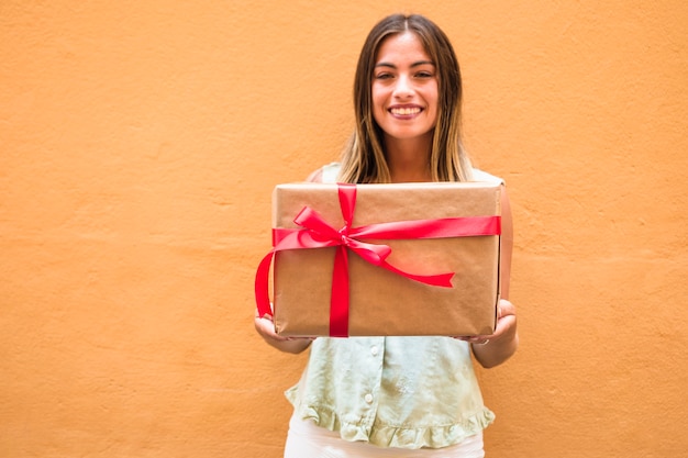 Foto gratuita sonriente mujer joven con caja de regalo atada con cinta roja