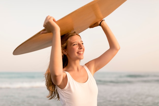 Sonriente, mujer joven, con, cuerpo, tabla, encima, el, cabeza, posición, delante de, mar