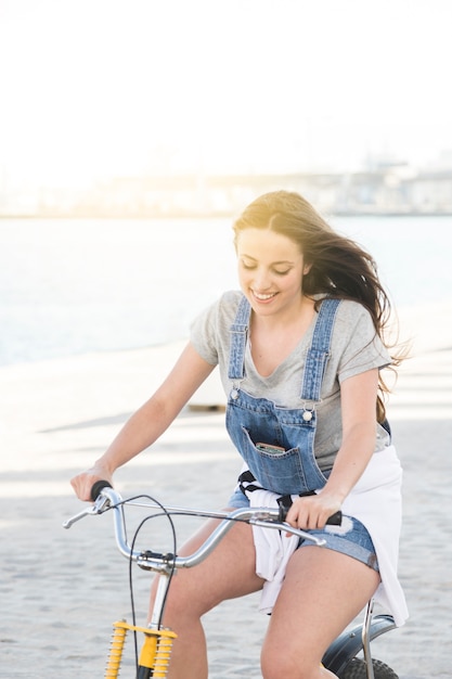 Foto gratuita sonriente, mujer joven, equitación, bicicleta