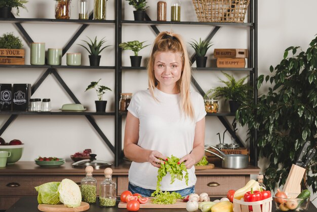 Sonriente mujer joven rubia con lechuga cortada en la mano