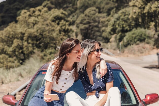 Sonriente mujer joven sentada en el coche disfrutando