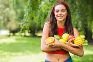 Foto gratuita sonriente mujer joven con verduras frescas y frutas en las manos