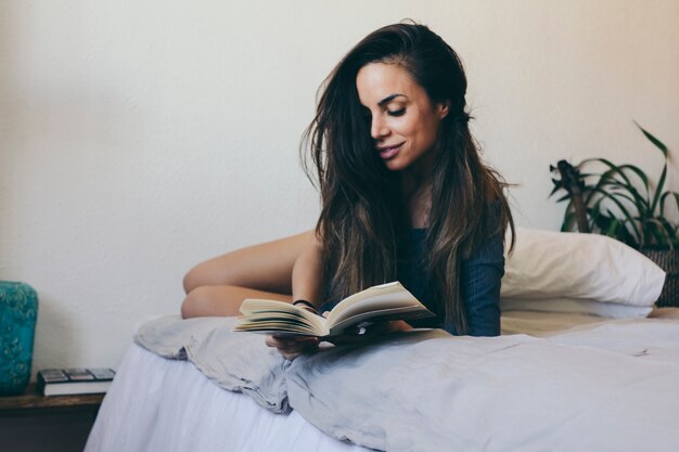 Sonriente mujer leyendo en la cama