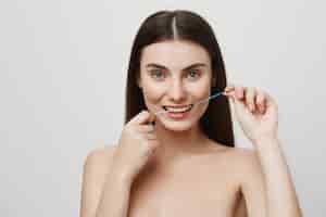 Foto gratuita sonriente mujer linda usar hilo dental con hilo dental