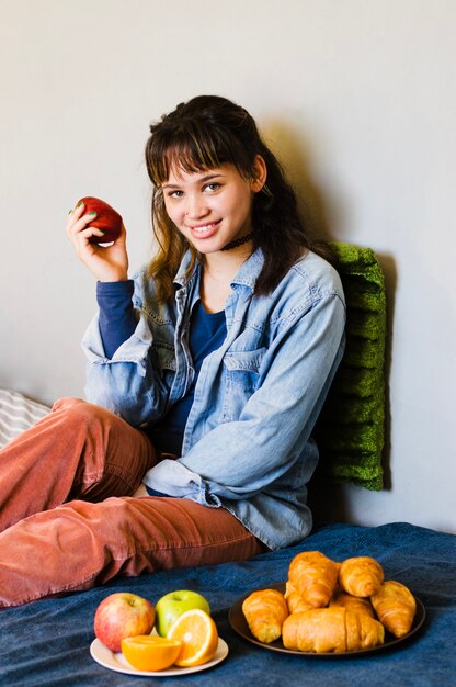 Sonriente mujer con manzana en la cama