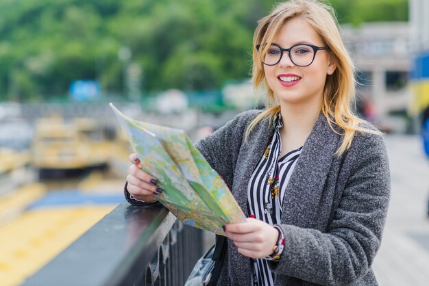 Sonriente mujer con mapa en el pasamanos