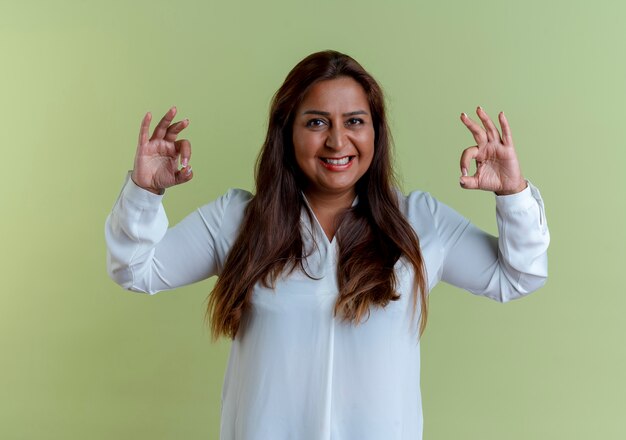 Sonriente mujer de mediana edad caucásica casual mostrando okey gesto aislado en verde oliva