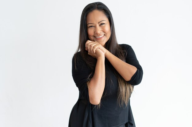 Sonriente mujer de mediana edad con las manos juntas.